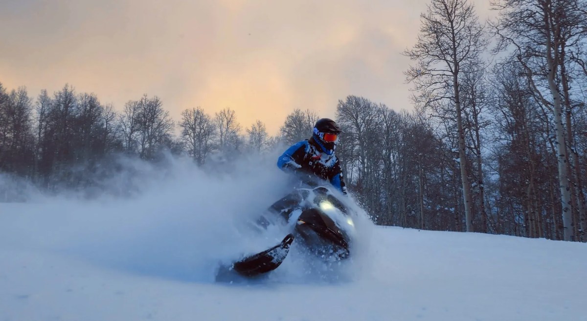 utah-powder-snowmobiling-scaled a man riding skis down a snow covered slope