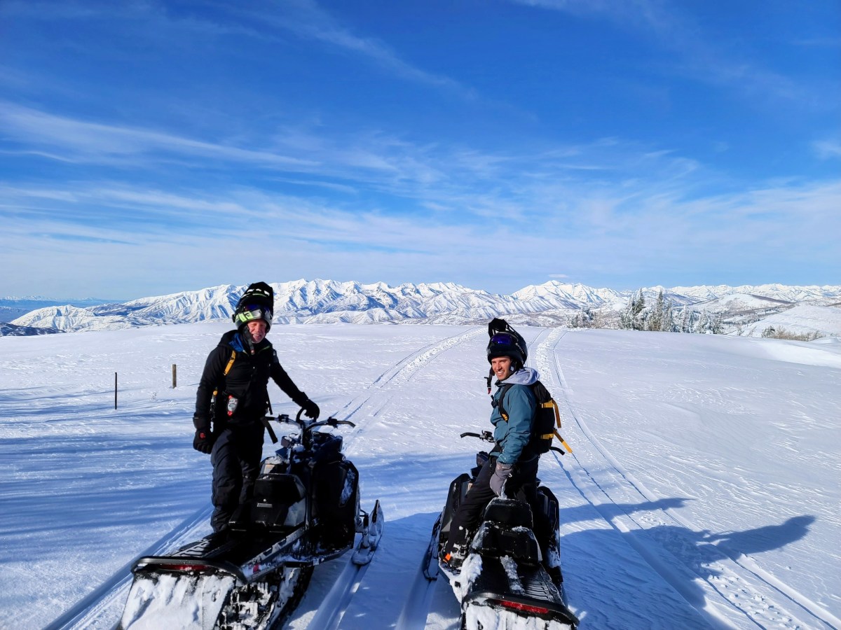 Group snowmobile tour traveling along a snowy mountain trail near Park City.