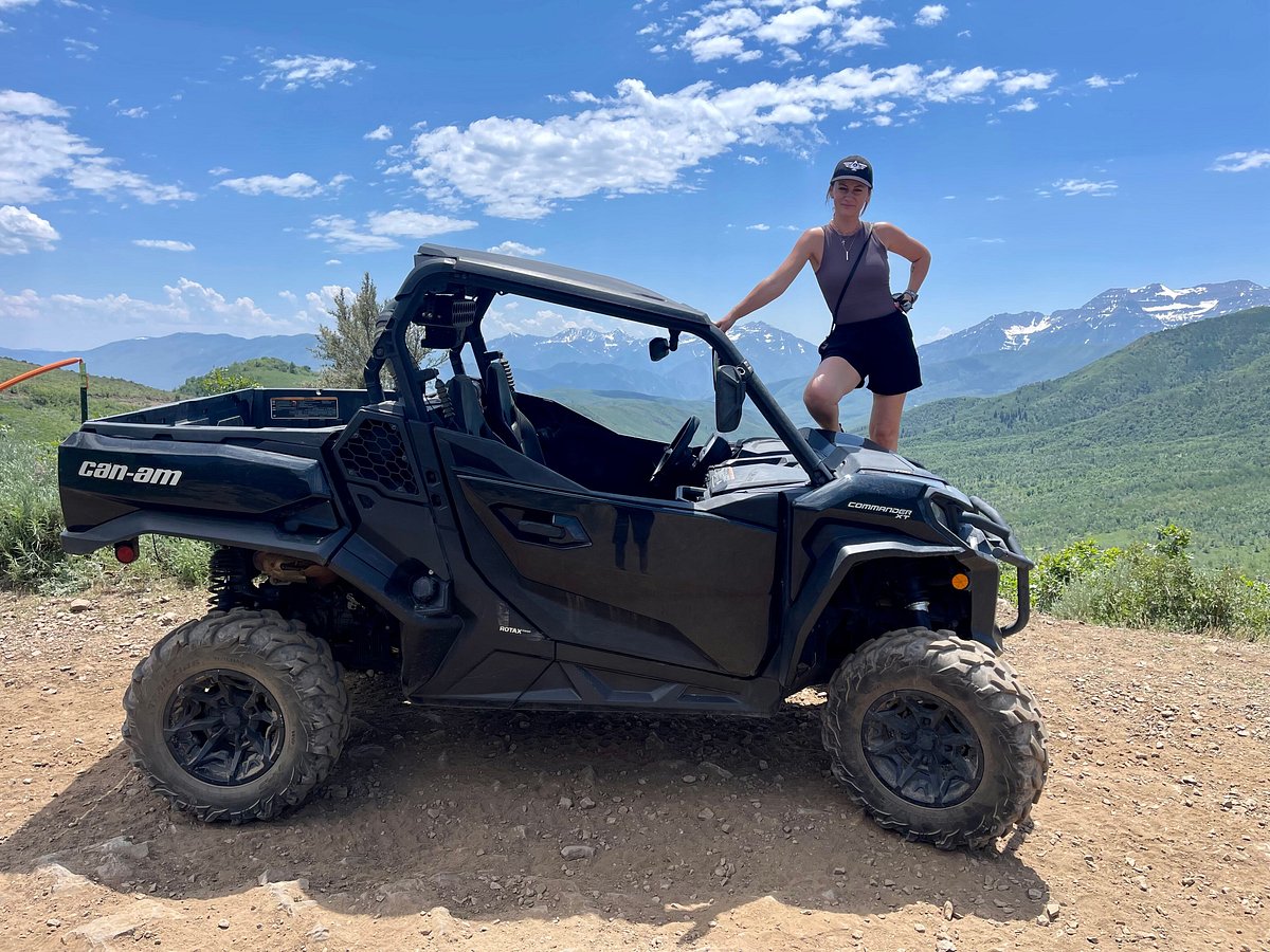 A woman standing above a UTV on a dirt trail in Heber City, Utah, surrounded by rugged terrain.