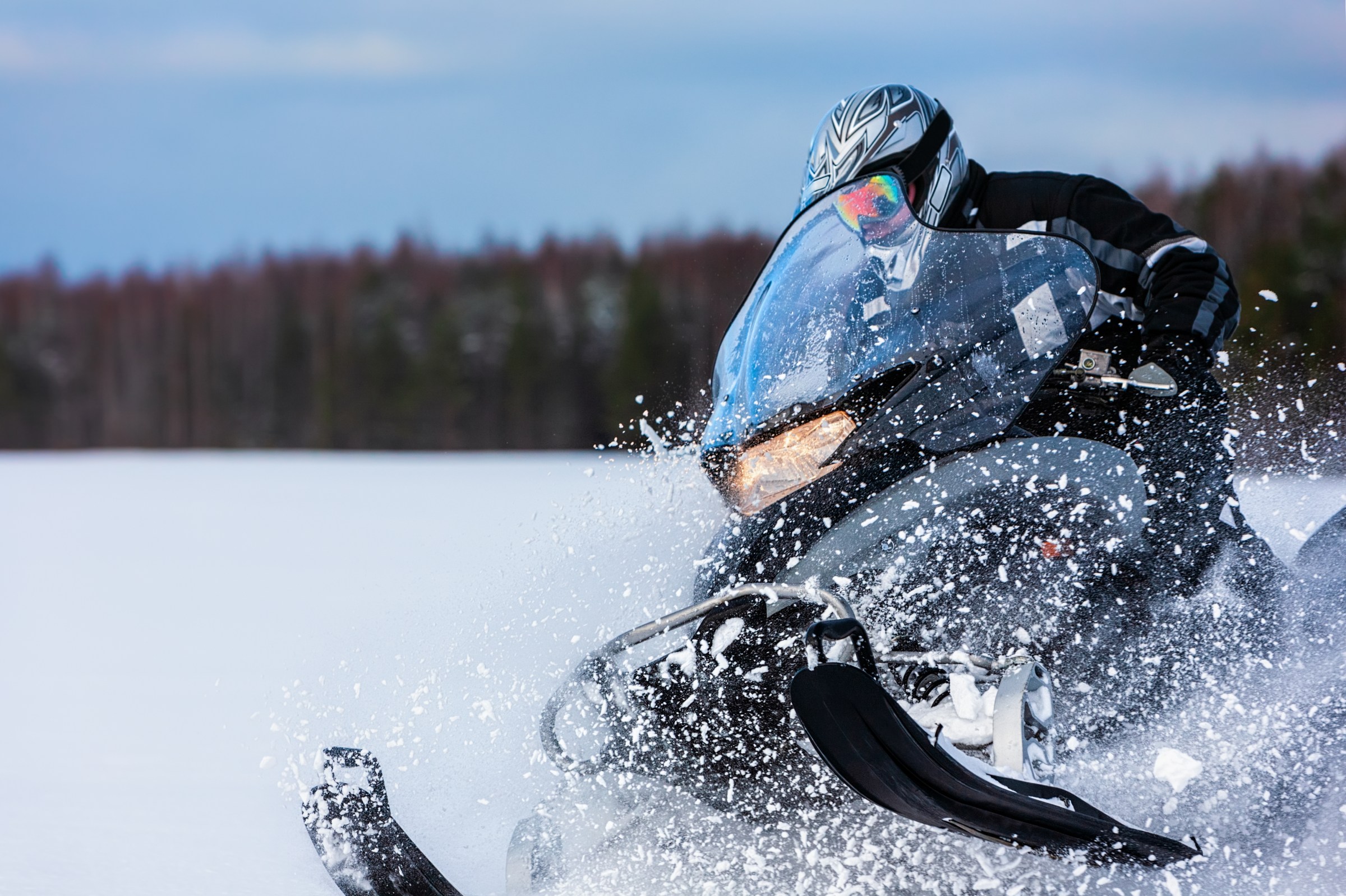 Snowmobile rider speeding through a deep snowdrift in Utah’s backcountry, kicking up clouds of white powder while enjoying an exhilarating winter adventure across the pristine landscape.