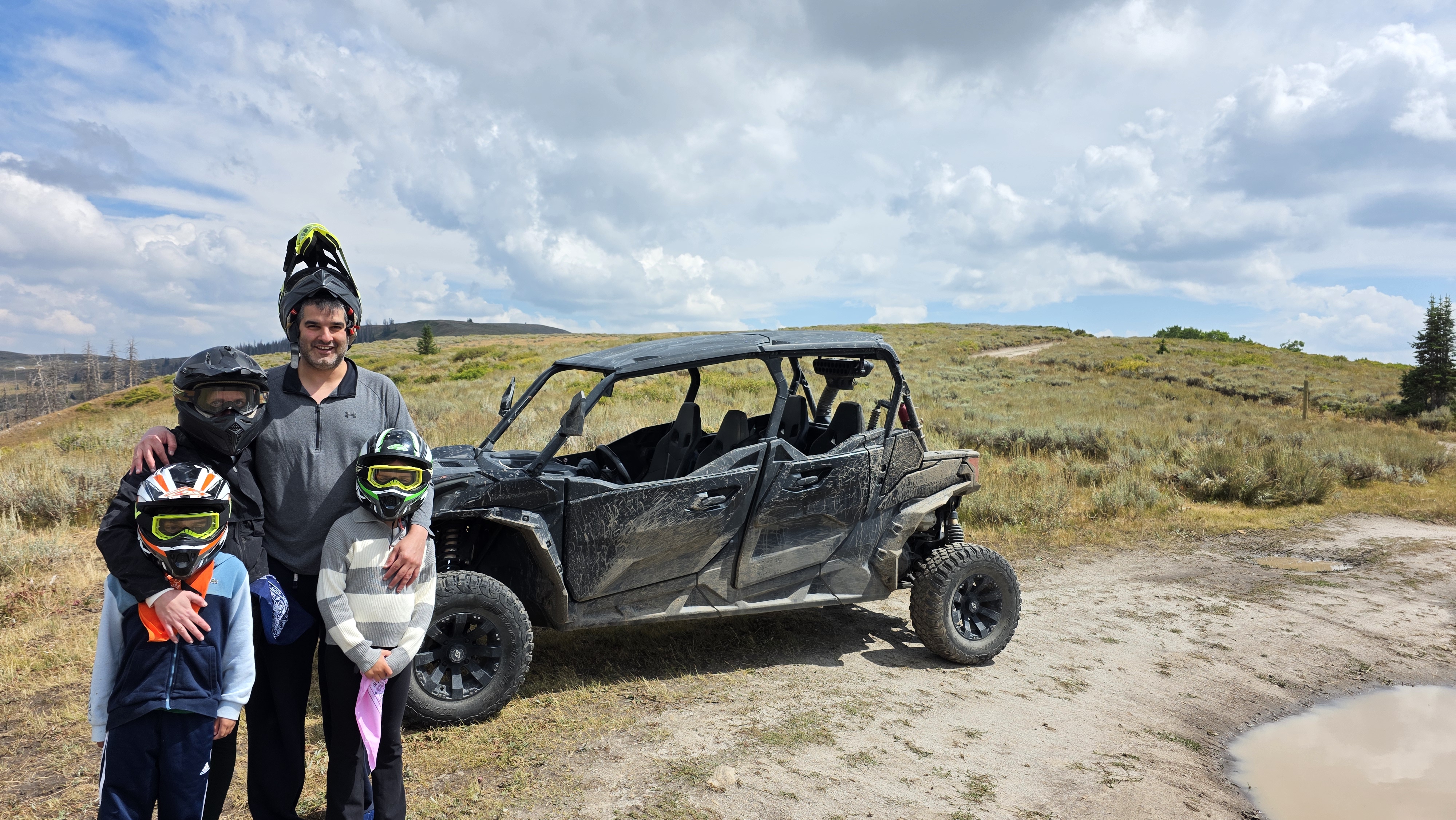 A father and 3 children posing in front of a Can-Am on their self-guided UTV tour in Heber City, Utah.