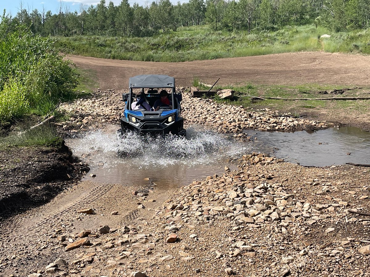 A couple riding through a trail puddle in Cascade Springs on a self-guided UTV tour in Utah.