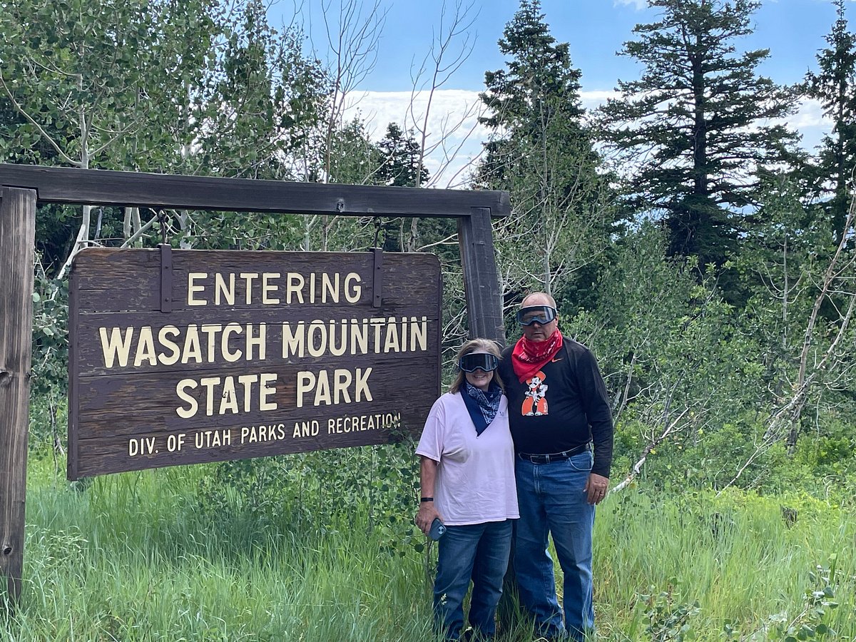 A couple standing in front of the Wasatch Mountain State Park parks and recreation sign.
